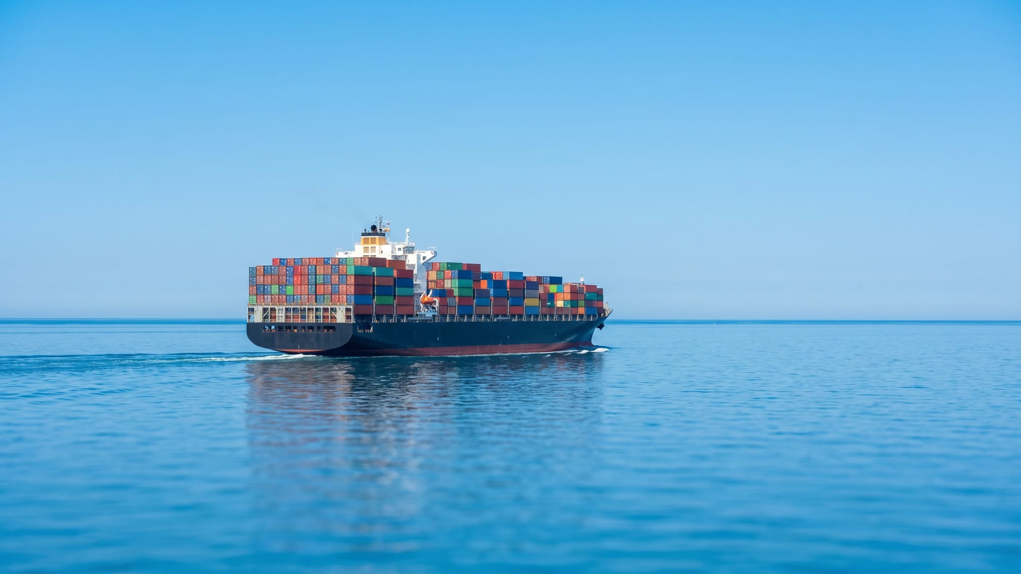 A container ship crossing a calm sea under a clear sky